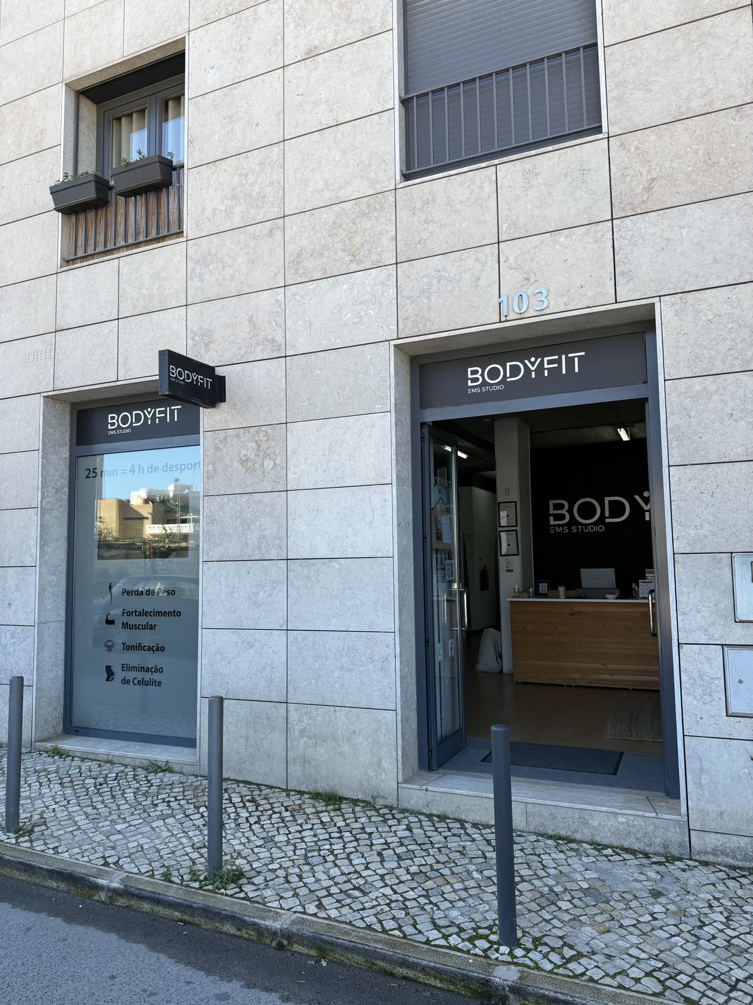 Fachada do BODYFIT EMS Studio na Rua Campo de Ourique 103, Lisboa, com a entrada aberta e a receção visível ao fundo.
